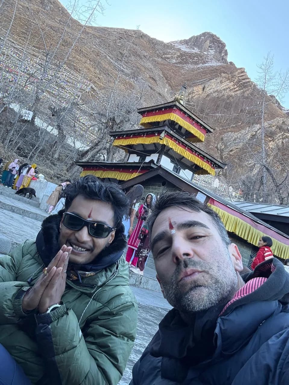 Rohit and a guest at Muktinath temple with the pagoda and prayer flags behind them, red tika on their foreheads